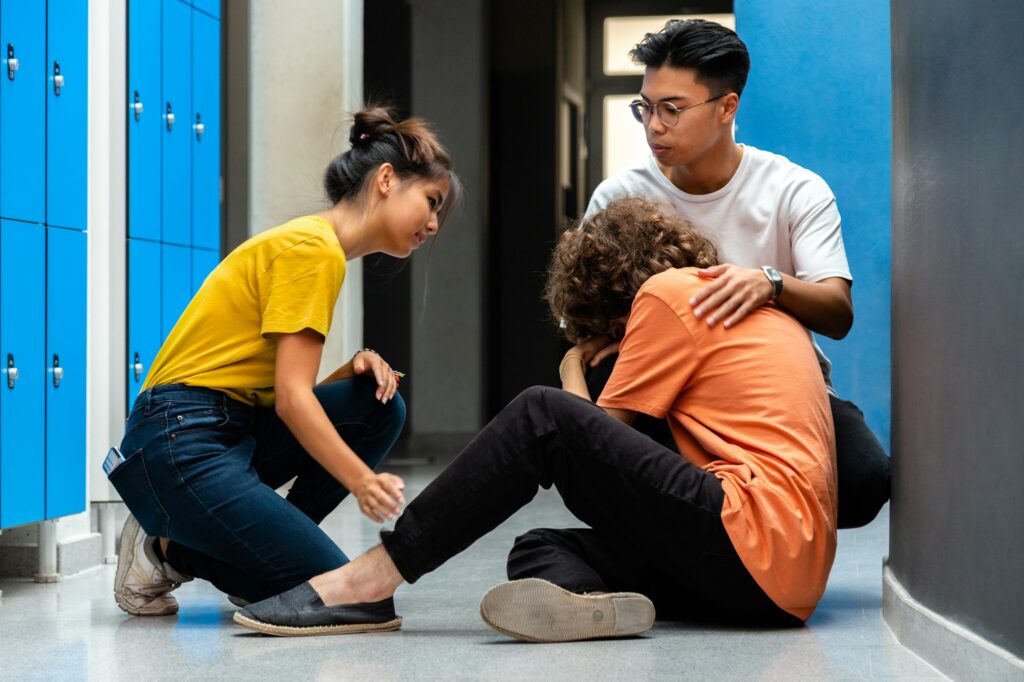 Two students comfort sad classmate who is victim of bullying