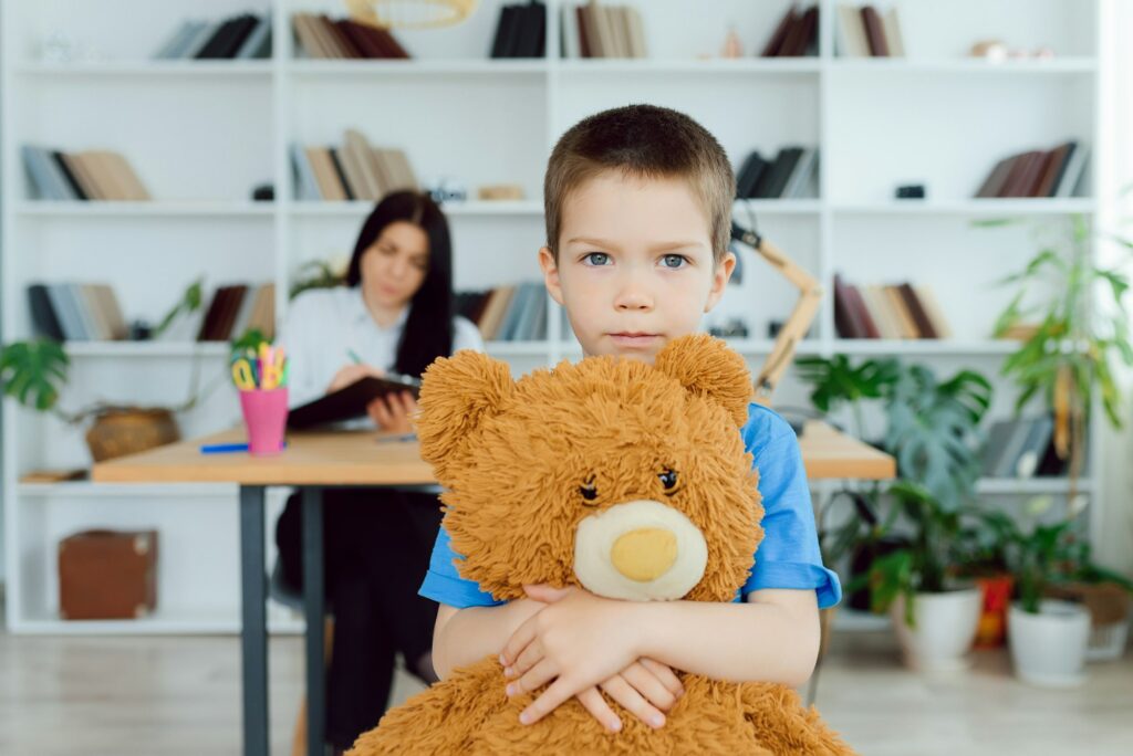 Young female psychologist working with little boy in office